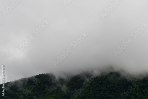 Fog moving over the top of dark green mountain