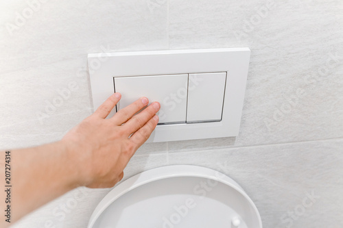 Hand pressing toilet flush button photo