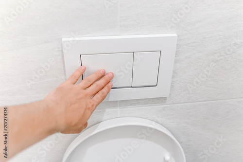 Fotografia Hand pressing toilet flush button