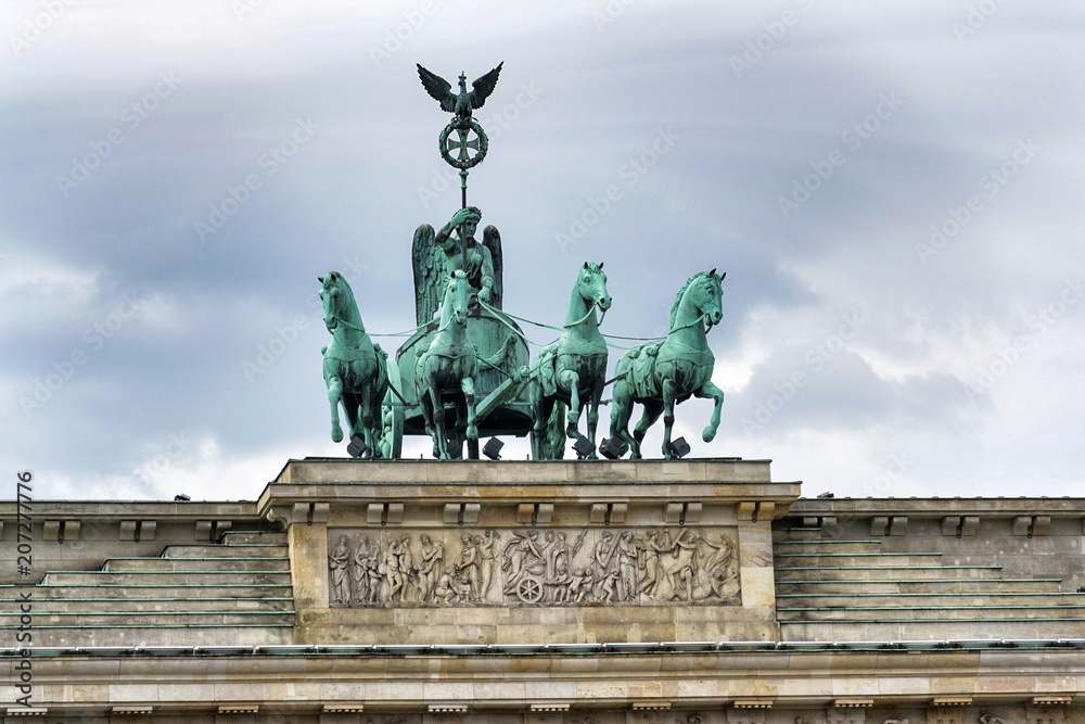 Quadriga on the neoclassical monument Brandenburg Gate with dramatic cloudy sky background, Berlin, Germany