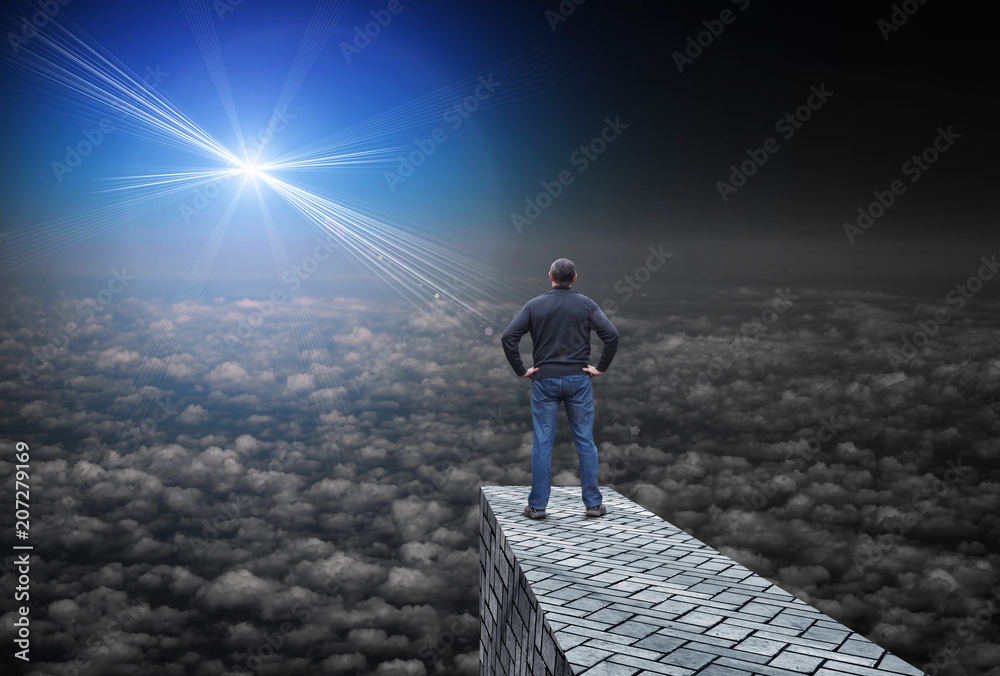 Far bright star illuminates the darkness, and the man standing above the clouds and looks at her Far bright star illuminates the darkness, and the man standing above the clouds and looks at her