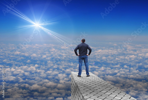 Bild auf Leinwand Man stands over the clouds and looks at a distant bright star above the horizon