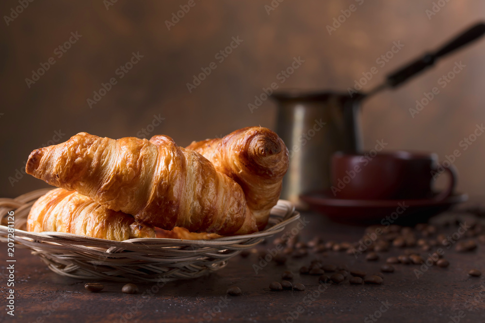 Fresh and tasty croissant  and cup of coffee on old copper background.