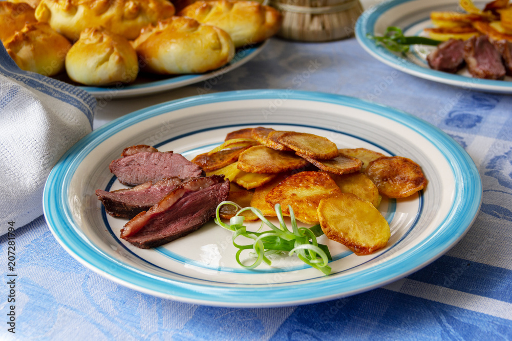 Fried potatoes, goose breast and green onions