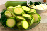 Cut zucchini slices, green dill, whole zucchini, a plate with chopped garlic and sour cream - ingredients for cooking snacks.