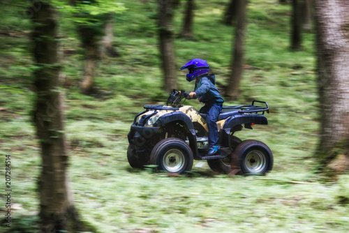 The boy is traveling on an ATV.