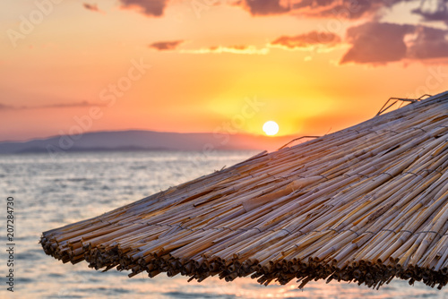 Colorful sunrise on the beach against the background of the sea and the mountains.