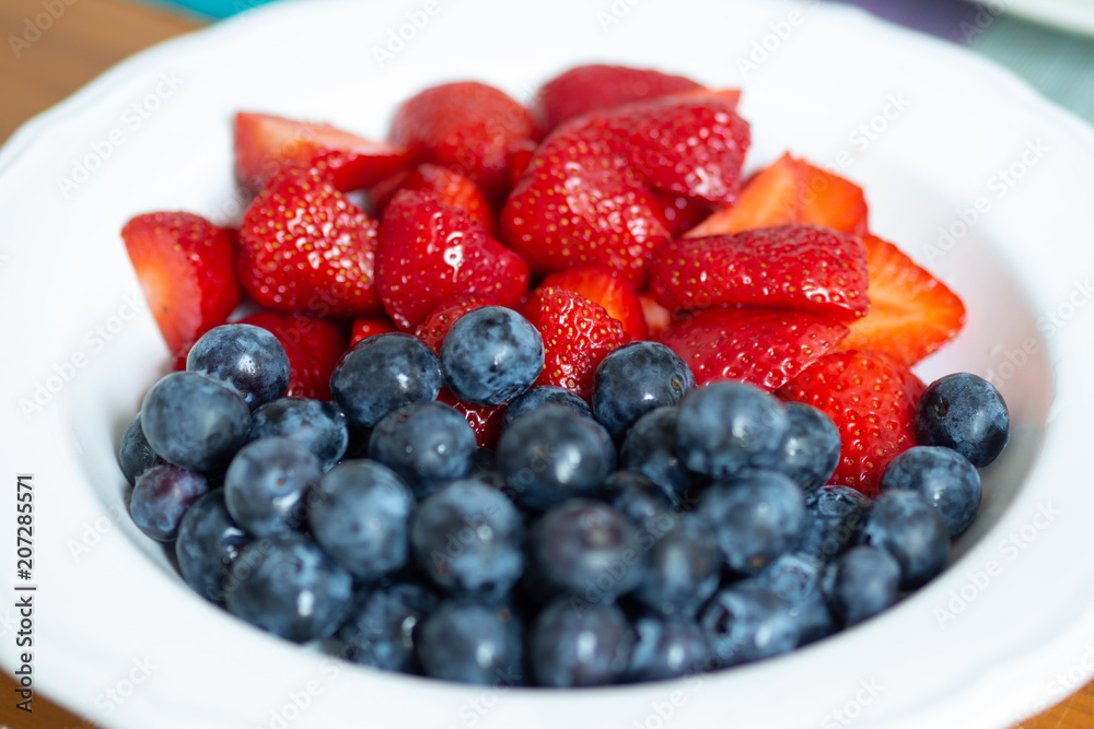 Strawberries and blueberries in a white bowl Strawberries and blueberries in a white bowl