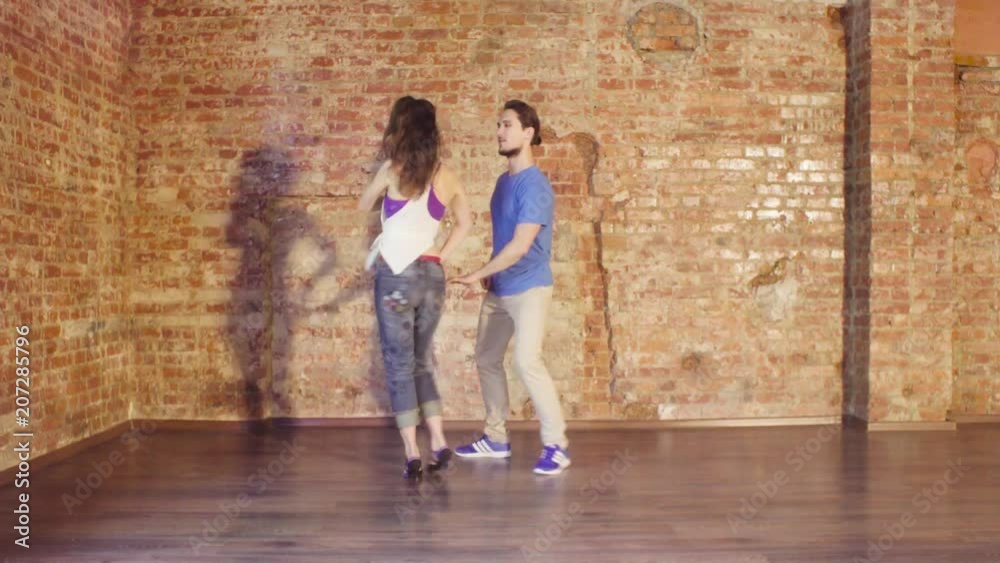 Couple dancing in the hall on the background of old brick wall Couple dancing in the hall on the background of old brick wall