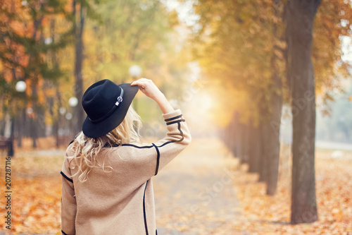 Young woman in black hat looking in the distanse in the autumn park. photo