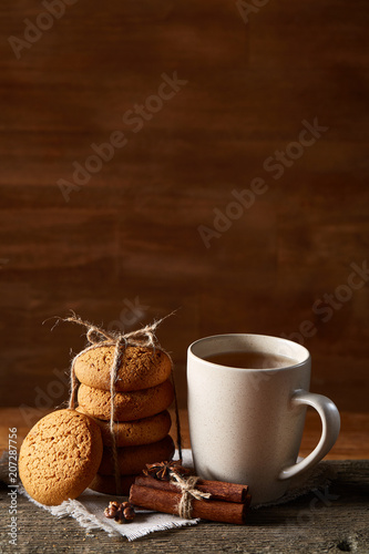 Traditional Christmas tea concept with a cup of hot tea, cookies and decorations on a wooden table, selective focus