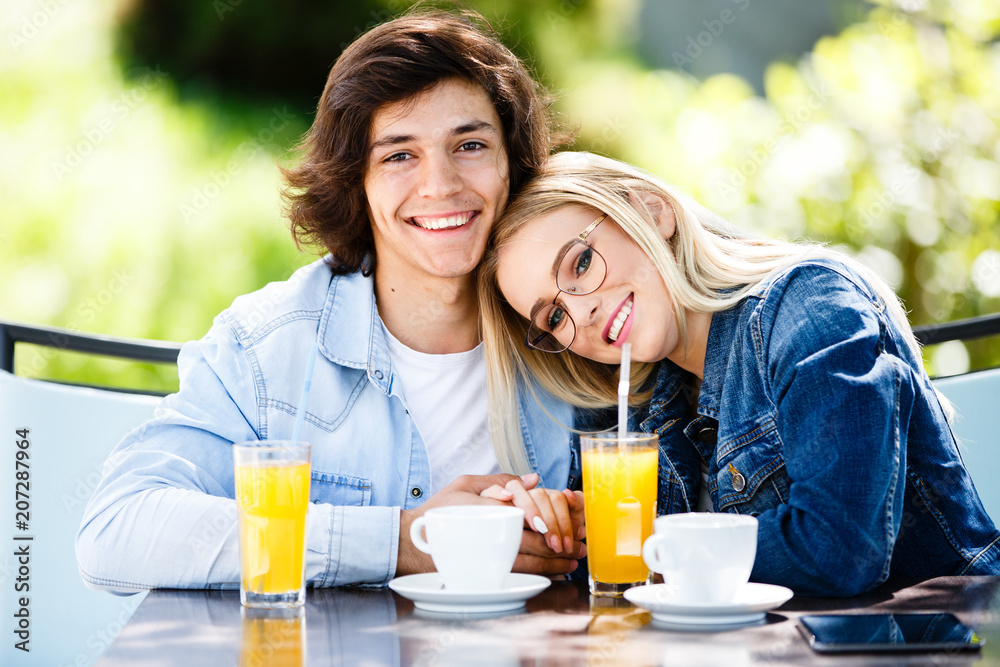Young romantic couple spending time together - sitting in cafe's garden Young romantic couple spending time together - sitting in cafe's garden
