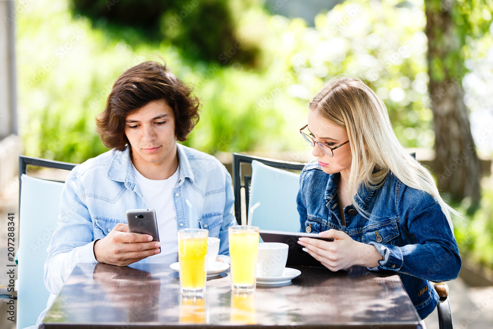 Young couple using tablet and phone while sitting together at cafe Young couple using tablet and phone while sitting together at cafe