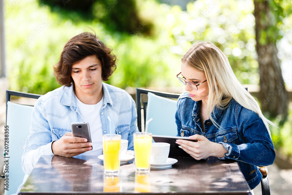 Young couple using tablet and phone while sitting together at cafe Young couple using tablet and phone while sitting together at cafe