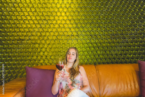 Beautiful woman tasting wine with wine bottles in background