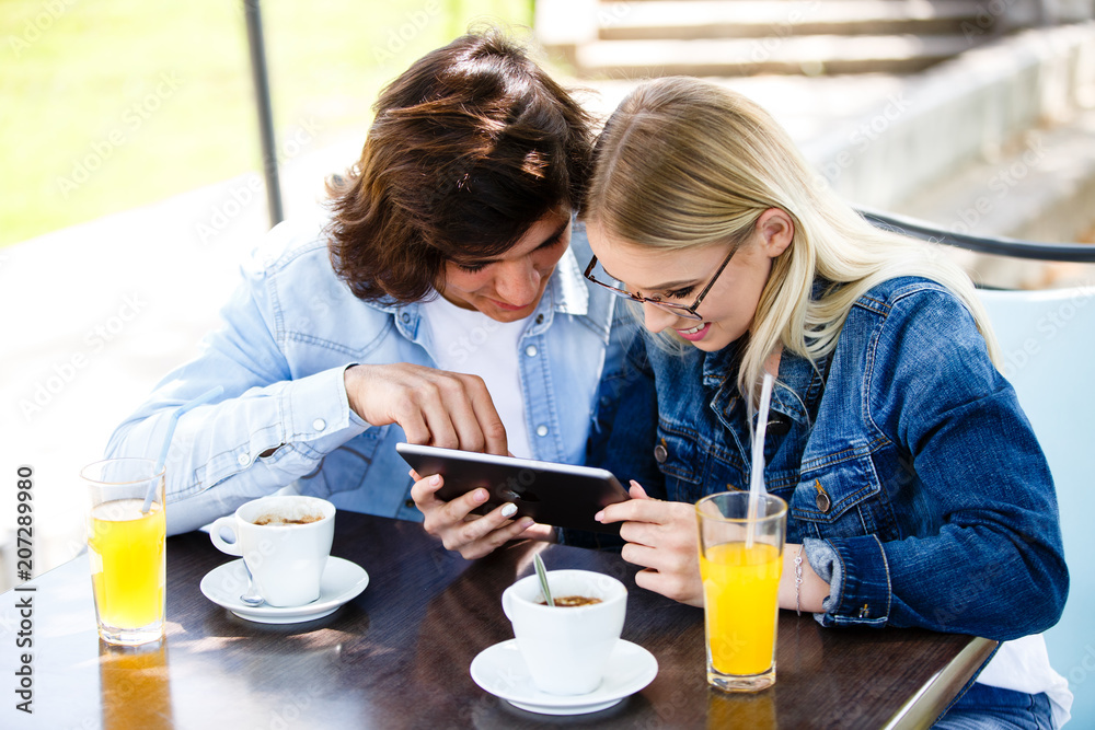 Young couple using tablet while sitting together at cafe