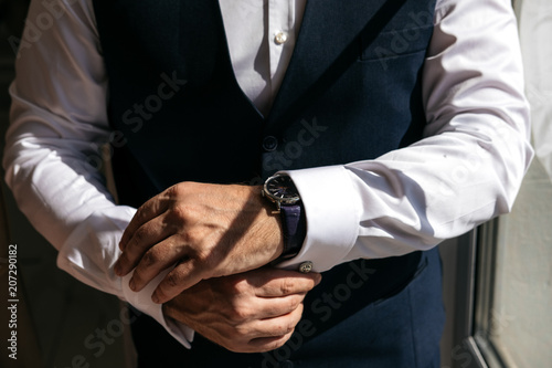 A man in a business suit zips up shirt cuffs