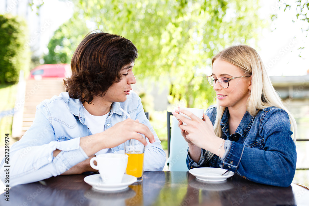 Young romantic couple spending time together - sitting in cafe's garden, drinking beverage Young romantic couple spending time together - sitting in cafe's garden, drinking beverage