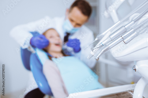 Dentist service. Attentive dentist bowing head while examining his patient