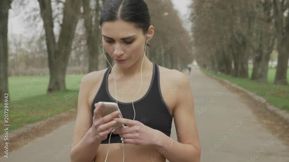 Young fsport girl is turning on music on her smartphone, running, healthy lifestyle, sport conception