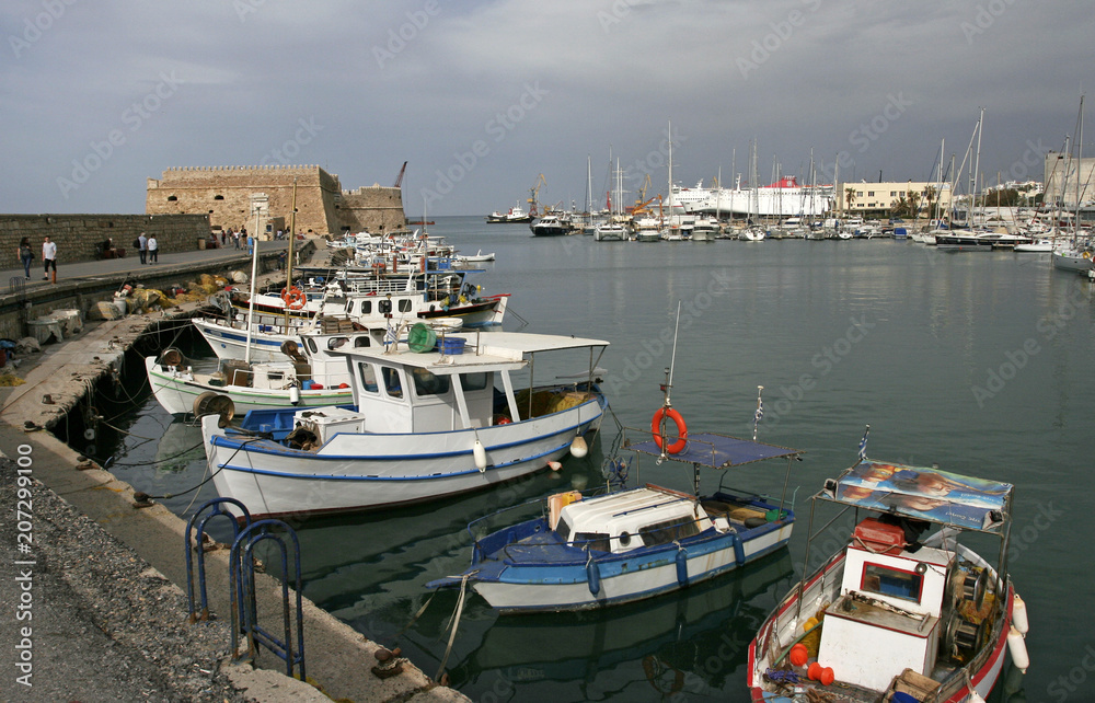 The white boats in the marina near the old fortress in the small Mediterranean town on the sunny day.