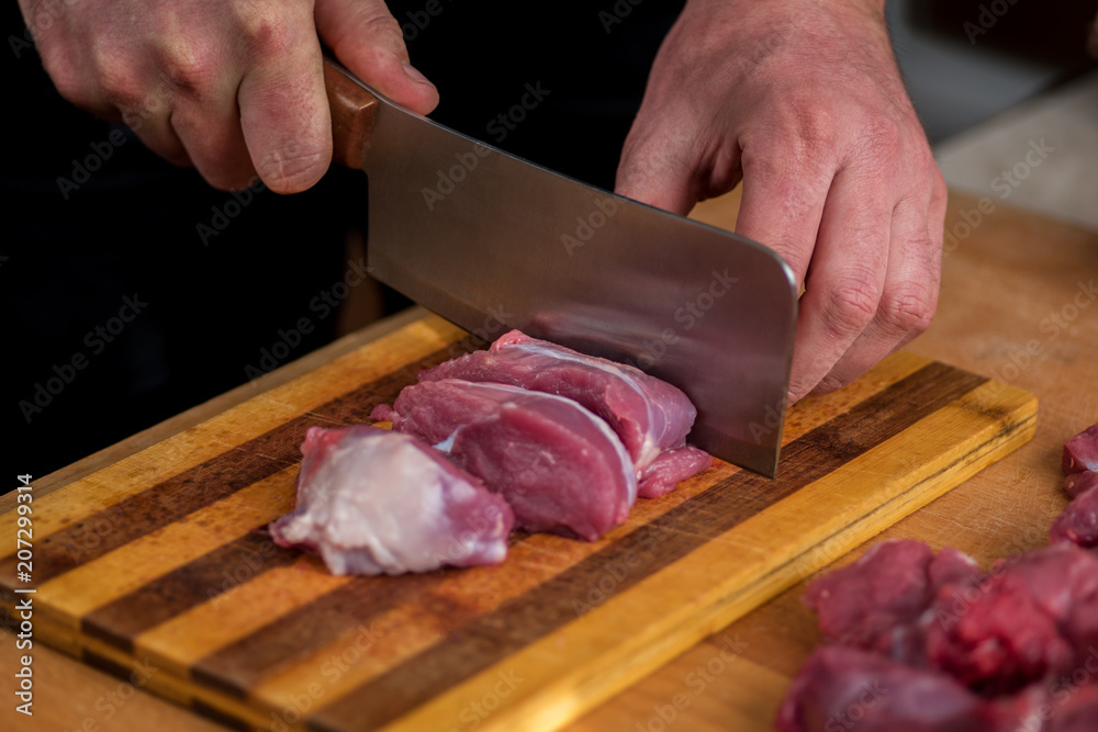 Man is cutting beef on an old board