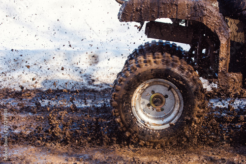 hand in yellow leather boot standing on the steps of the ATV standing in a muddy puddle