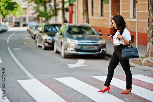 Stylish african american business woman on streets of city at pedestrian crossing Fototapet