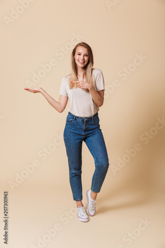 Full length portrait of a happy girl pointing finger away
