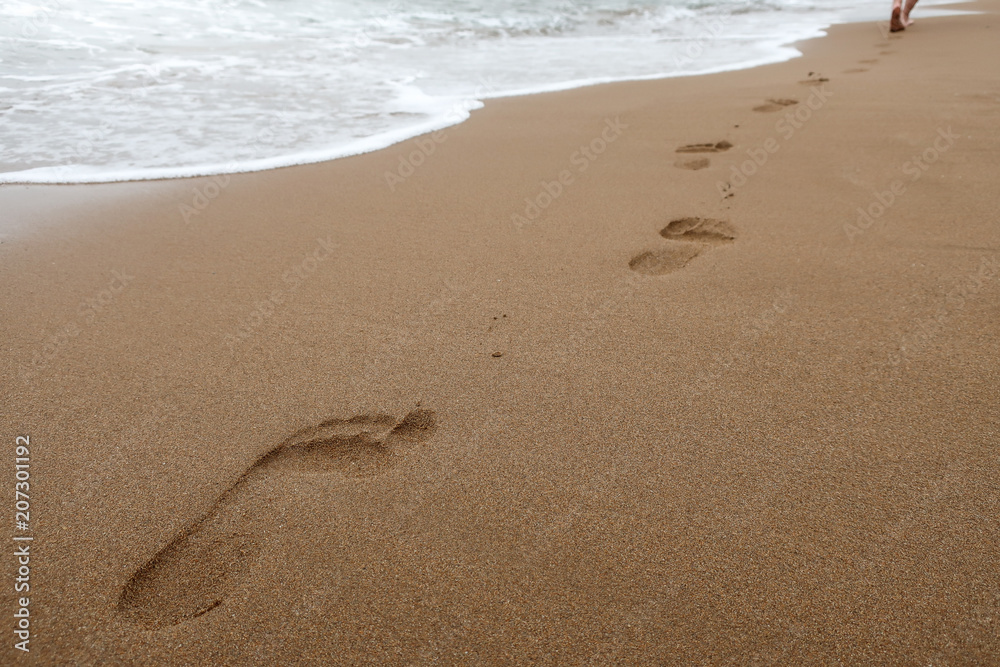 Close up of footprints in wet sand on the beach at sunset. Concept for traveling to tropical / exotic places, vacation and holiday. Close up of footprints in wet sand on the beach at sunset. Concept for traveling to tropical / exotic places, vacation and holiday.