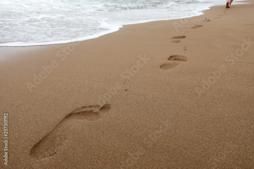 Close up of footprints in wet sand on the beach at sunset. Concept for traveling to tropical / exotic places, vacation and holiday. © Forenius