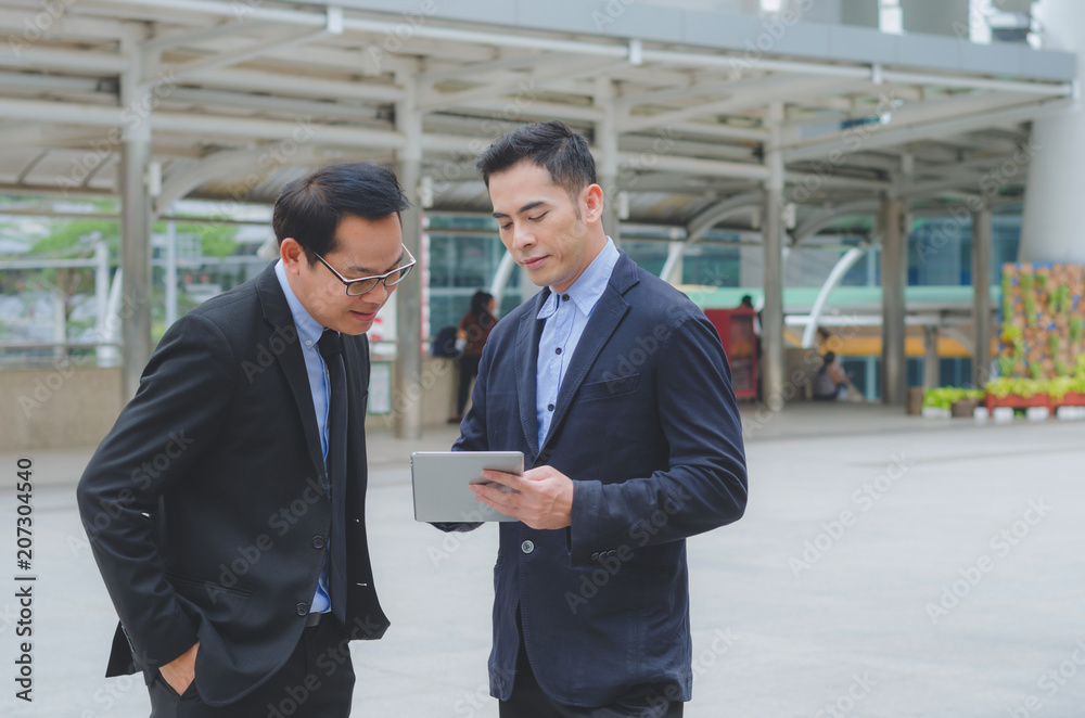 two attractive business man using touching pad on smartphone and tablet technology connecting social online with discussion about business strategy growing.