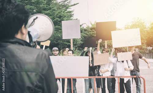 Group of protesters holding protest signs walking at the street