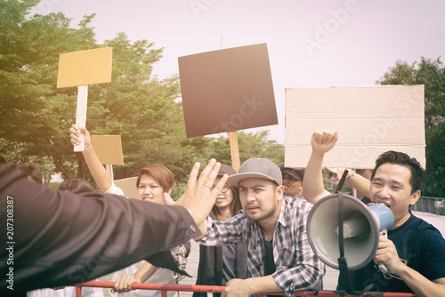 Group of protesters holding protest signs walking at the street