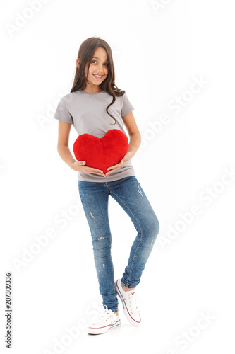 Cute girl standing isolated holding heart in hands.