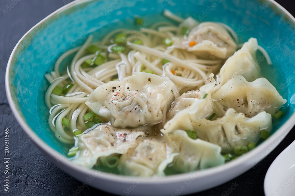Blue bowl of noodle soup with wontons, selective focus, closeup, horizontal shot Blue bowl of noodle soup with wontons, selective focus, closeup, horizontal shot