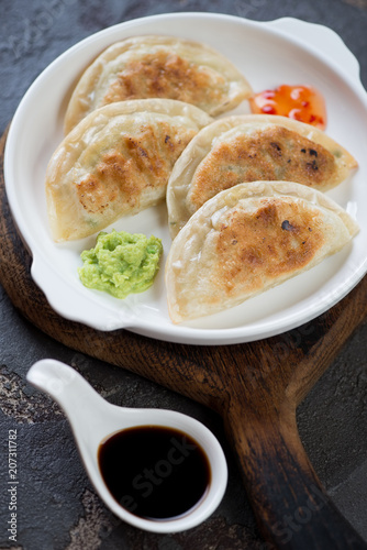 Close-up of fried korean potstickers with dipping sauces, vertical shot, selective focus