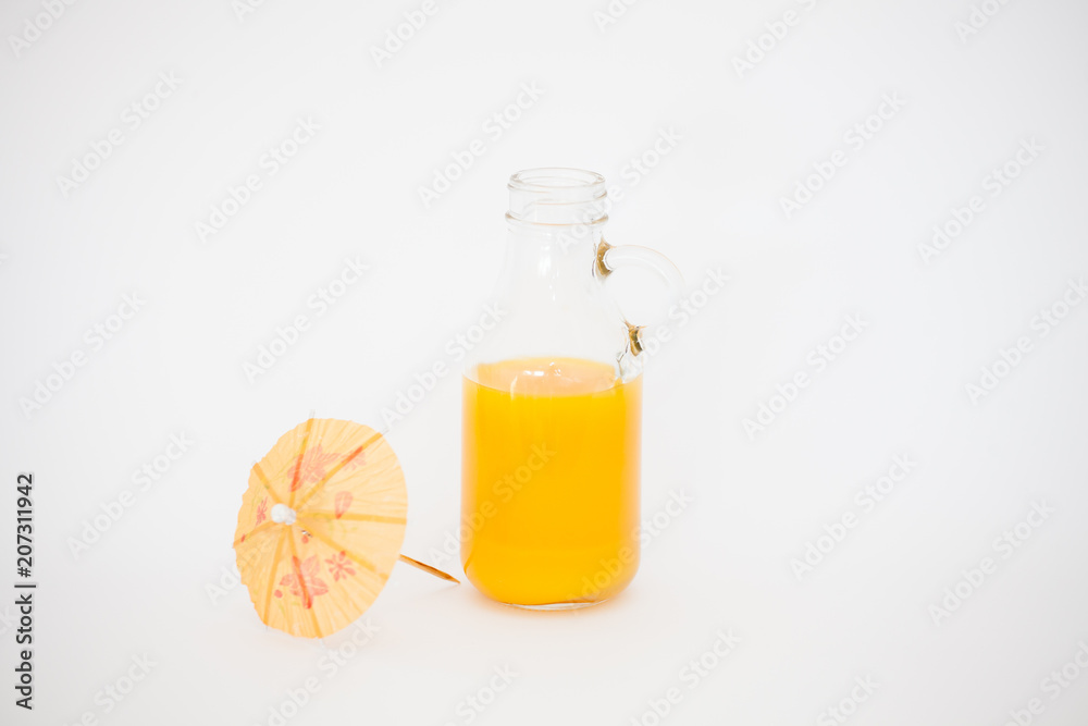 Orange juice in the original glass bottle and paper umbrellas on a white background