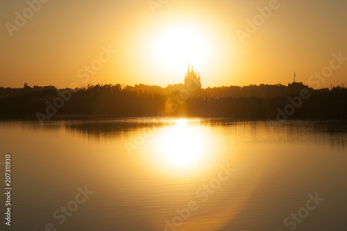 Beautiful sunset on a lake with church dome on a sunset background