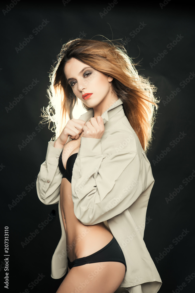 Sexy slim lady with makeup wear male shirt, black background. Girl with nude  belly and loose shirt looks seductive. Girl in black underwear looks sexy  and attractive. Femininity concept Stock Photo