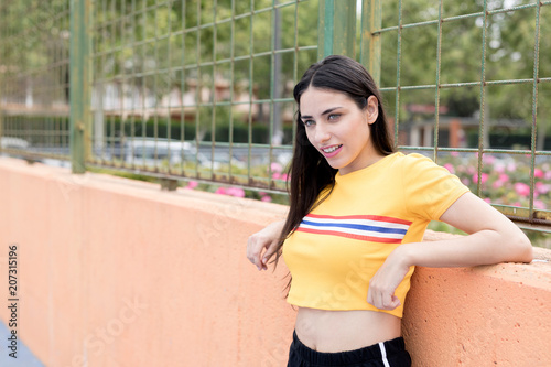 Young slim woman standing leaning on fence