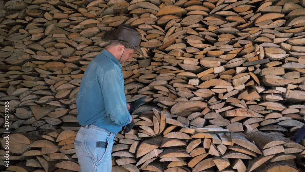 Portrait Of A Manly Man In A Cowboy Hat In Warehouse Holding A Bunch Of Firewood