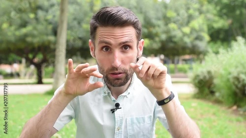 Handsome brunette young man in light green shirt try to hypnotize someone by saying 