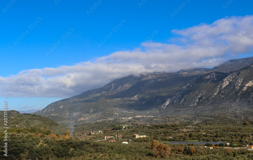 Panorama of mountain valley in Taygetos range on Peloponnese peninsula in Greece, with olive prunning fire and solar farm