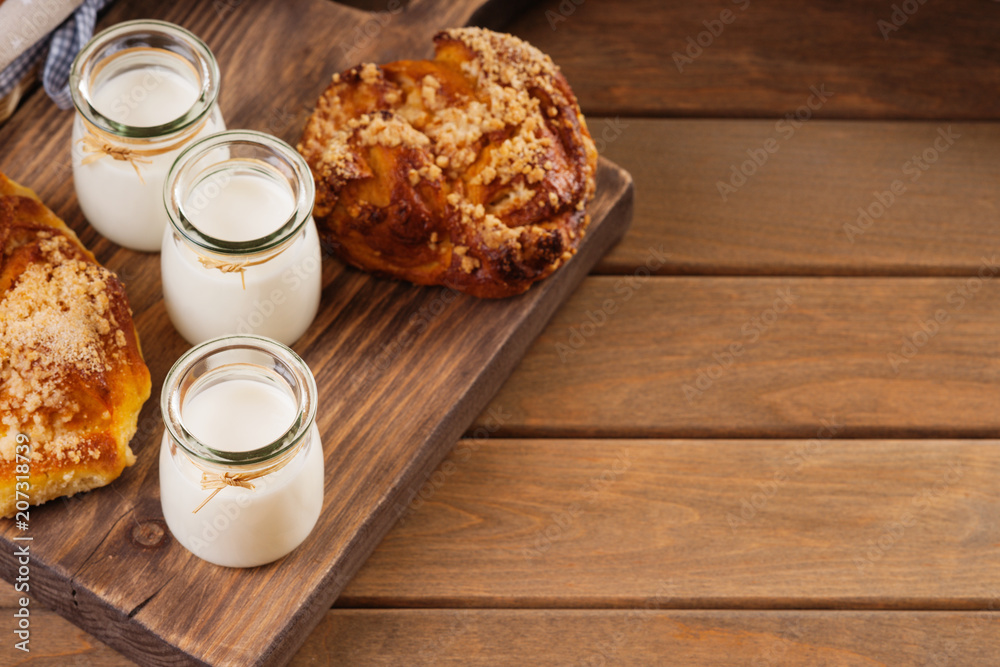 Jars with milk and bread buns on a cutting board Jars with milk and bread buns on a cutting board