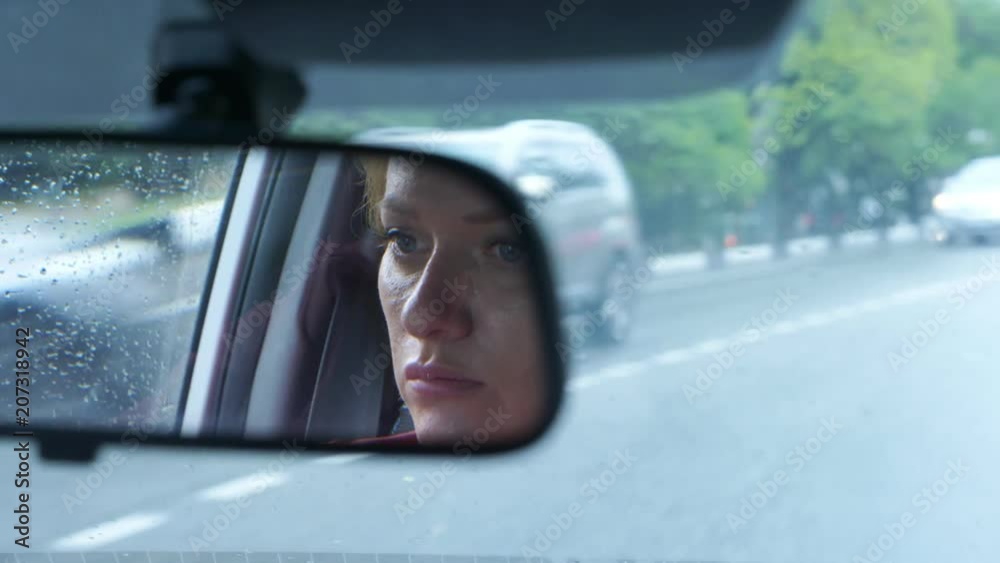 Reflection of a woman's face with blue eyes in rearview mirror, woman behind the wheel. 4k, slow motion