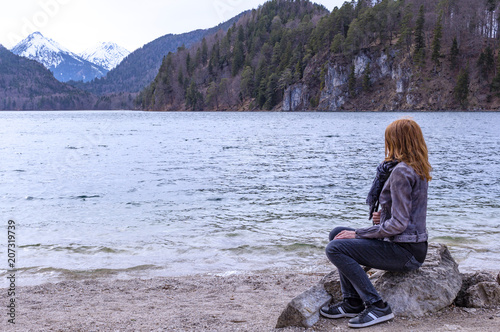 Woman sitting on stone look at the Lake and mountains