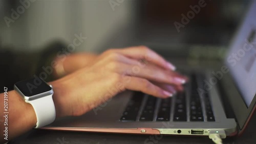 Close-up of business woman hands with smartwatch typing on laptop keyboard in the office. Working process. Data input.