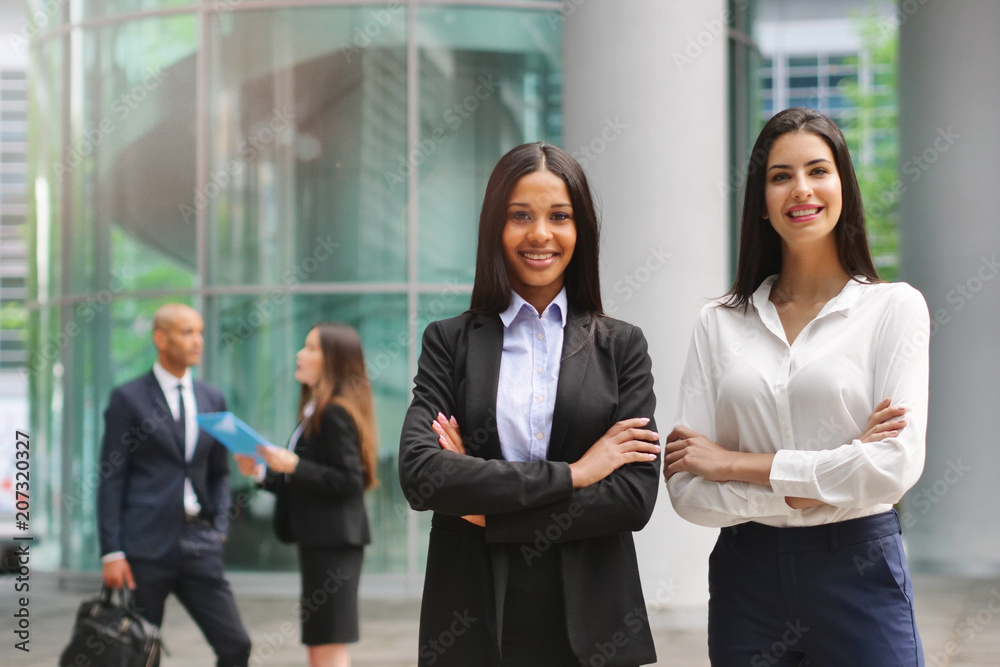 Portrait of business people of different ethnic backgrounds dressed in suits, they smile and cross their arms. Concept of: internationality and career, cooperation and team. Portrait of business people of different ethnic backgrounds dressed in suits, they smile and cross their arms. Concept of: internationality and career, cooperation and team.