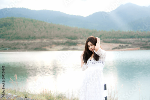 Portrait of happy smiling asian woman wear white dress standing at lake on sunny summer day.